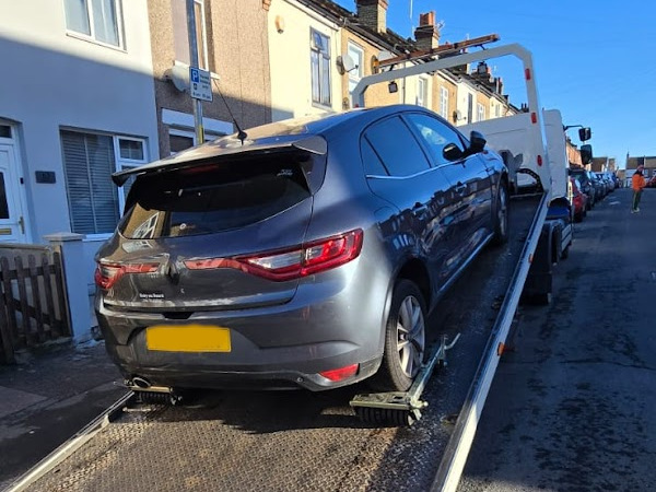 Prompt Recovery DAF LF flatbed truck loading a grey Renault Megane hatchback on a residential street in bright sunshine