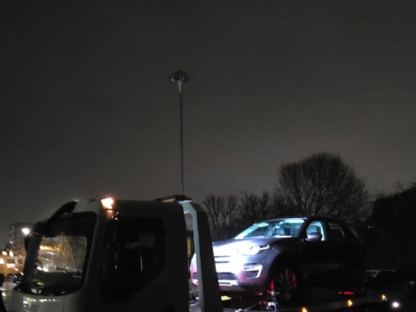 Prompt Recovery flatbed truck at night in wet conditions with a Land Rover Discovery Sport loaded on the bed