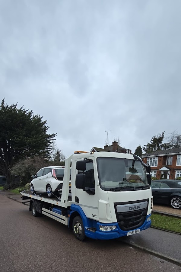 Prompt Recovery DAF LF flatbed truck with a white Nissan Leaf electric car loaded, collected from a residential street on an overcast day