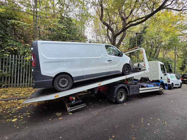 White panel van loaded on a Prompt Recovery DAF LF flatbed truck, parked on a tree-lined road in autumn
